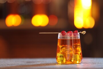 Glass of alcoholic cocktail with garnish on table against blurred background, space for text. Bokeh effect
