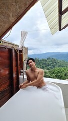 Man relaxing in an outdoor bubble bath with a scenic mountain backdrop on a transparent background