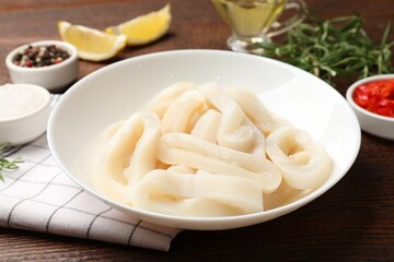 Uncooked squid rings and spices on wooden table, closeup