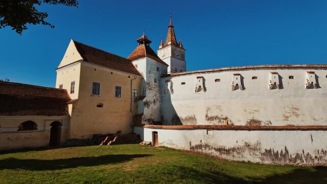 Harman Fortified Church, Harman, Transylvania, Romania, combines a white walled church, defensive ring, and robust tower, enclosing a calm courtyard that reflects centuries of community life