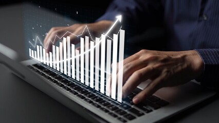 A professional workspace featuring hands typing on a laptop, complemented by digital graphics that illustrate financial growth and data analysis trends. Copula