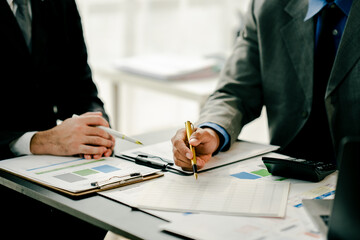 Young colleagues discuss business and analytical price charts using calculators and laptops to calculate financial, tax, accounting, statistics and analytical research ideas.