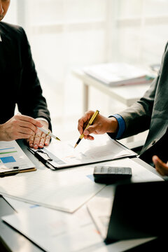Young colleagues discuss business and analytical price charts using calculators and laptops to calculate financial, tax, accounting, statistics and analytical research ideas.