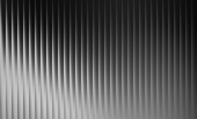 Abstract background with vertical ribbed texture in grayscale, creating a sense of depth and shadow play
