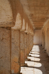 Stone colonnade on the coast of Portugal. Symmetry, shadows, light, depth. Architectural structure, geometry, rhythm, peaceful scene, ground-level view.