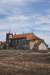 Fototapeta premium Old stone church with tiled roof at Cabo Espichel, Portugal. Historic architecture, dry landscape, religious symbolism, peaceful scene.