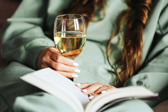 Woman relaxing with glass of wine and book. Cozy evening time at home in bedroom. Calm lifestyle with reading and drink. Female enjoying leisure in peaceful atmosphere. Rest after long day.