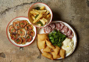 Italian appetizers - fried eggplant, french fries with herbs, salami, burrata, arugula salad, 