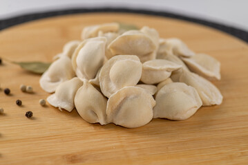 Frozen dumplings semi-finished product piled up decorated with spices on a board