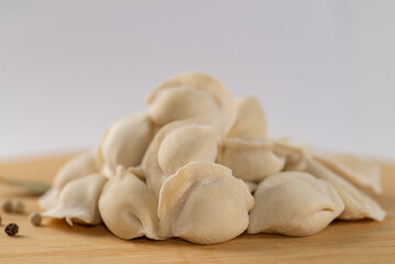 Frozen dumplings semi-finished product piled up decorated with spices on a board