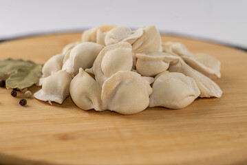 Frozen dumplings semi-finished product piled up decorated with spices on a board