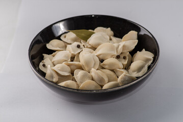 Frozen dumplings semi-finished product piled up decorated with spices on a plate