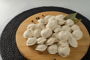 Frozen dumplings semi-finished product piled up decorated with spices on a board