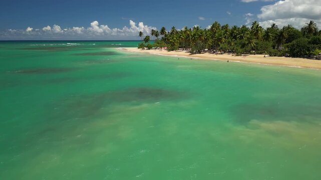 4K aerial view of Punta Popy Beach &mdash; bright sky and turquoise Caribbean shore. Best for vacation marketing and airline ads.