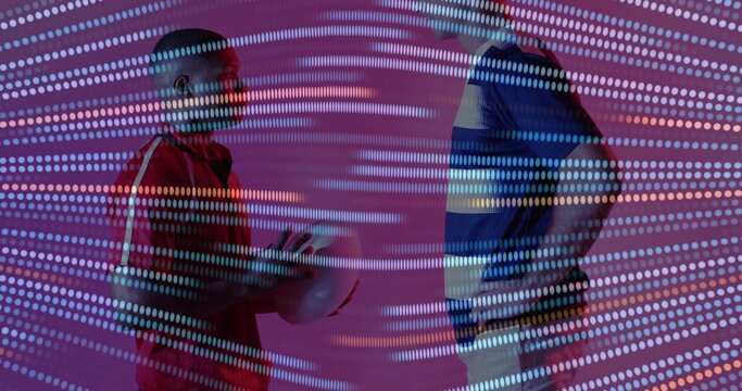 Standing two men wearing jerseys facing off in studio, holding ball with digital dot projection - Powered by Adobe