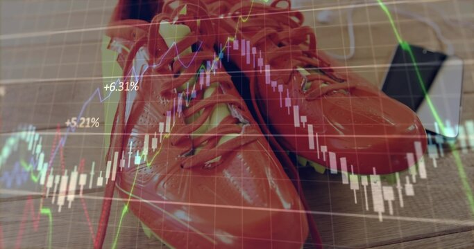 Fototapeta Showcasing glossy red sports shoes resting on wooden tabletop over tablet, displaying chart overlay