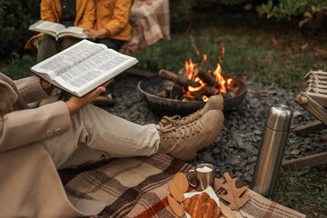 Cozy outdoor gathering with books, fire, and autumn treats.
