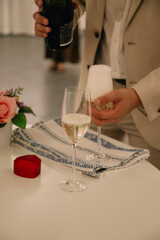 A man pours champagne into a glass. Solemn moment  of  engagement or proposal . Romance , celebration .