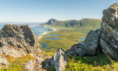 View from Laupen mountain on Vesterålen islands towards Røyken Royken mountain, Bleik. Beautiful hiking destination in arctic Norway, great outdoors. Rocks, grass and wild flowers in  foreground