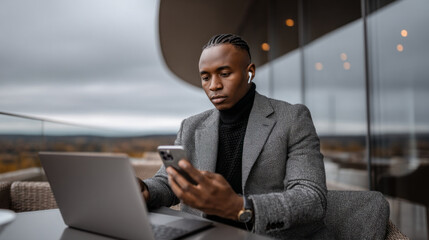 Businessman works on laptop while outdoors at a modern cafe during a cloudy afternoon