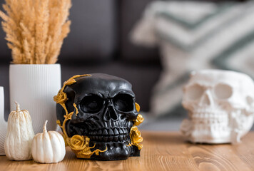 Halloween celebration. A black skull with golden roses and pumpkins on the table. Decor for the Day...