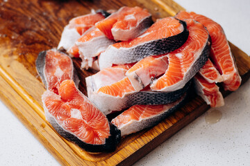 Sliced pieces of red fish lie on a wooden board in the kitchen.