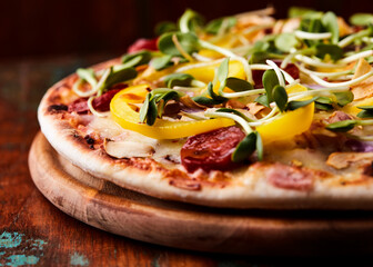 Pizza with salami, mozzarella cheese, black olives and pepper. Rustic wooden background. Soft focus. Copy space.	