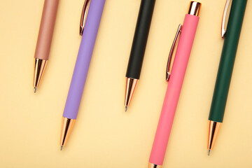 New stylish colorful pens on beige background.