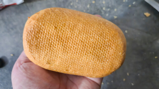 A hand holding a sponge-like textured object resembling a beehive, highlighting its unique shape and surface. Ideal for product demonstrations or DIY projects.