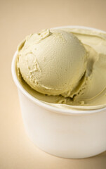Pistachio gelato scoop in white cup close-up