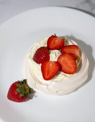 Classic Pavlova Dessert with Whipped Cream and Fresh Strawberries Served on White Plate for Premium Sweet Object and Gourmet Food Concept