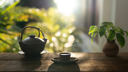 Tea cup and tea pot on wooden table with pothos plant
