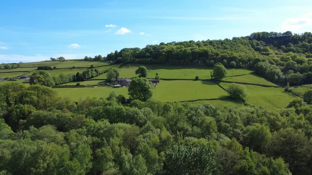 aerial drone view of Calder Valley West Yorkshire scenery with farms and meadows surrounded by trees near the village of Luddenden