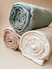 Fototapeta premium Soft muslin blankets in pastel colors rolled and stacked with eucalyptus leaves