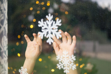 boy dressed as an elf placing snowflakes on the window
