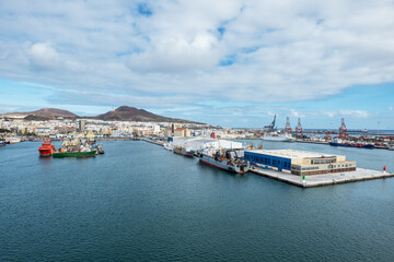 Fototapeta premium Panoramic view of the port of Las Palmas, Gran Canaria. The image captures a busy harbor scene with multiple ships, cranes, and industrial buildings