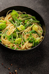 Spaghetti vegetables green peas, broccoli, string beans, kohlrabi vegetarian pasta tasty snack fresh delicious gourmet food background on the table rustic top view copy space vegan food