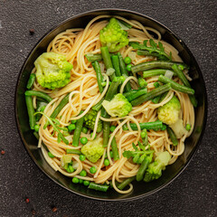Spaghetti vegetables green peas, broccoli, string beans, kohlrabi vegetarian pasta tasty snack fresh delicious gourmet food background on the table rustic top view copy space vegan food