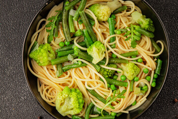 Spaghetti vegetables green peas, broccoli, string beans, kohlrabi vegetarian pasta tasty snack fresh delicious gourmet food background on the table rustic top view copy space vegan food