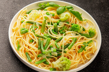 Spaghetti vegetables green peas, broccoli, string beans, kohlrabi vegetarian pasta tasty snack fresh delicious gourmet food background on the table rustic top view copy space vegan food