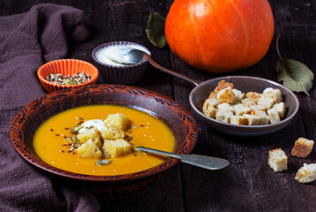 Pumpkin cream soup served with croutons, cream, and seeds.