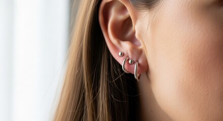 Close-up of female wearing multiple silver earrings on left ear