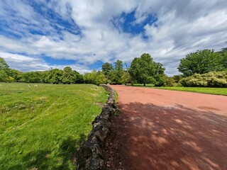 Red walking path with stone wall and green park