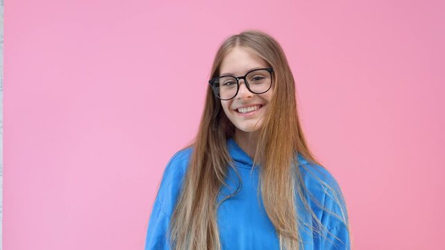 Cute young girl with glasses and hoodie on isolated background, portrait of student or schoolgirl or nerd