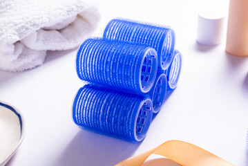 Set of Blue Plastic Hair Rollers with Hair Care Products on White Table