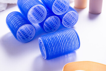 Set of Blue Plastic Hair Rollers with Hair Care Products on White Table