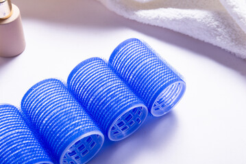 Set of Blue Plastic Hair Rollers with Hair Care Products on White Table