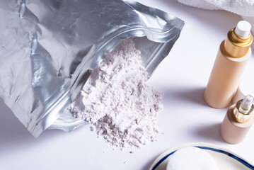 Alginate Face Mask in Plastic Bag with Professional Cosmetic Products on White Table