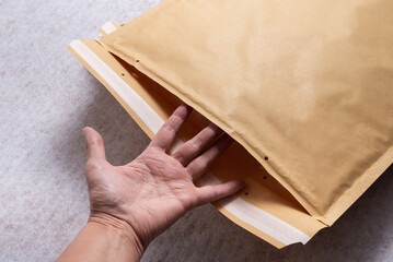 Female Hand Opening Bubble Mailer Plastic Padded Envelope on White Background, Top View