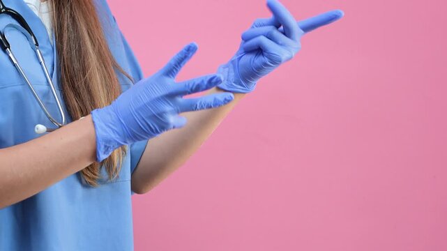 A doctor in a blue uniform puts on gloves against an isolated background